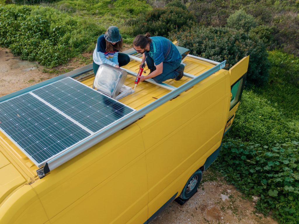 Bai and Den on the roof of the van, doing van build