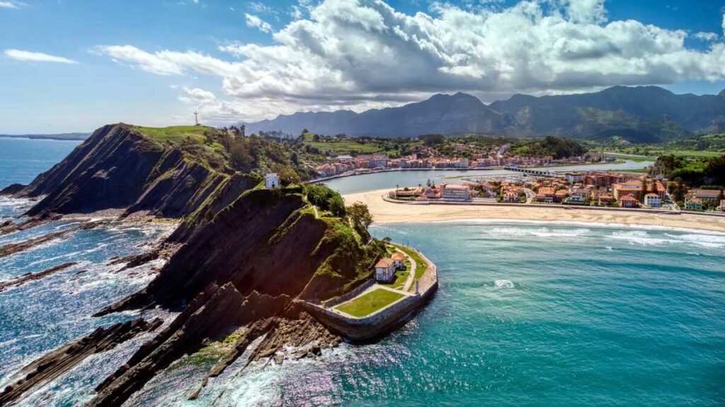 Luscious green headlands surrounded by crystal blue water and a sandy beach in the background