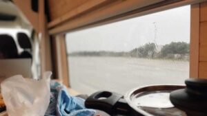 Black cooking pot with lid in front of window with rain outside