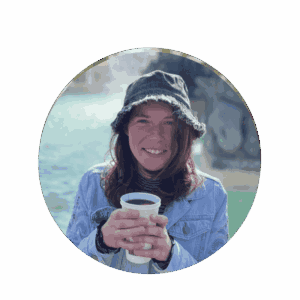 Portrait photo of a young woman wearing a black denim hat and light blue jacket with a mug in her hands