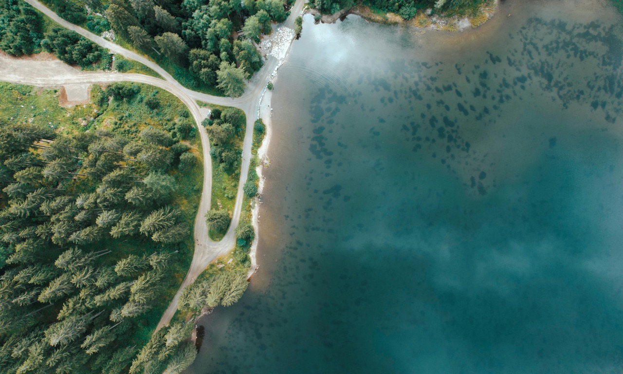 Bird view on a blue lake with walking routes and high green trees